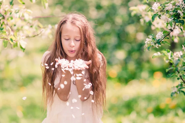 Прекрасная маленькая девочка в цветущем яблоневом саду в прекрасный весенний день — стоковое фото