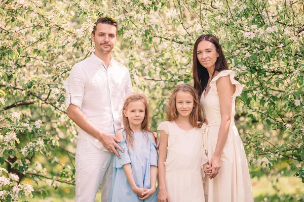 Adorável família no jardim florescendo cereja no belo dia de primavera — Fotografia de Stock