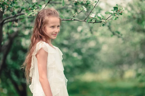 Liebenswertes kleines Mädchen im blühenden Apfelgarten an einem schönen Frühlingstag — Stockfoto