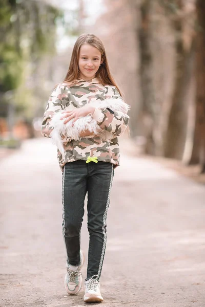 Mała dziewczynka z białym szczeniakiem. Szczeniak w rękach dziewczyny. — Zdjęcie stockowe
