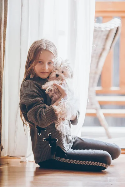 Beyaz köpek yavrusu olan küçük bir kız. Bir kızın ellerinde bir köpek yavrusu — Stok fotoğraf