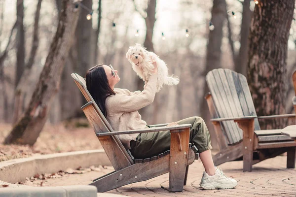 Frau mit einem weißen Welpen. ein Welpe in den Händen eines schönen Mädchens — Stockfoto