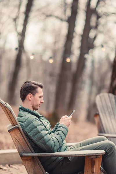 Kaukasische toerist jongen met mobiele telefoon buiten in café. Man die mobiele smartphone gebruikt. — Stockfoto
