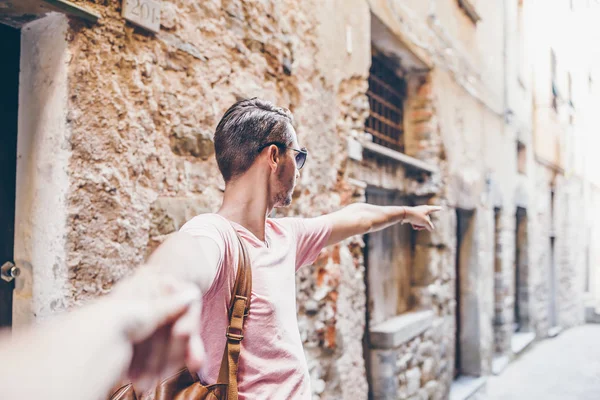 Fille suivant petit ami tenant la main dans la vieille rue européenne rire et sourire — Photo