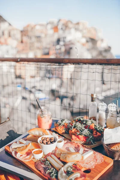 Smaczne przekąski włoski. Świeże bruschettes, sery i mięso na pokładzie w kawiarni na świeżym powietrzu, z niesamowitym widokiem w Manarola — Zdjęcie stockowe
