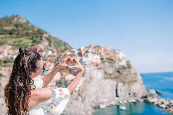 Šťastná dívka s rukama tvaru srdce na staré pobřežní vesnice v národním parku Cinque Terre. Evropské dovolená. — Stock fotografie