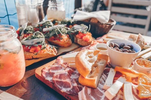 Tasty italian snack. Fresh bruschettes, cheeses and meat on the board in outdoor cafe with amazing view in Manarola — Stock Photo, Image