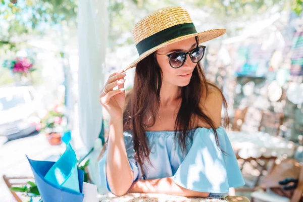 Portret van jonge mooie vrouw zittend in een cafe buiten koffie drinken. — Stockfoto