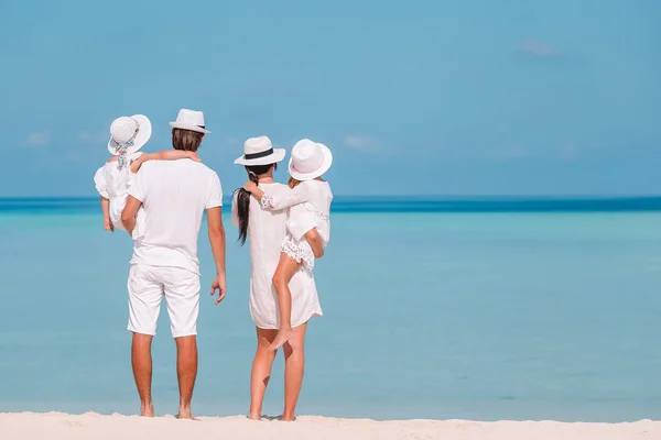 Счастливая семья из четырех человек на белом пляже — стоковое фото