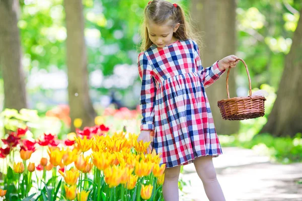 Liten bedårande flicka med blommor i tulpaner trädgård — Stockfoto