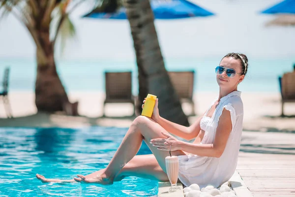 Mujer joven aplicando crema solar durante las vacaciones en la playa — Foto de Stock