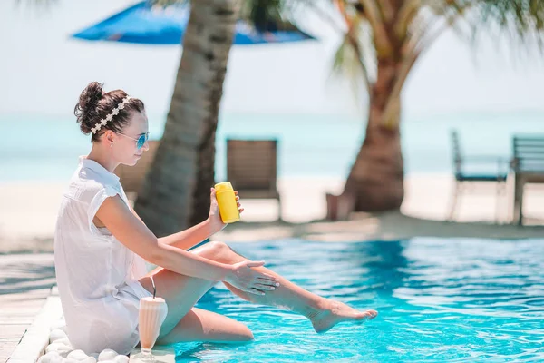 Mujer joven aplicando crema solar durante las vacaciones en la playa — Foto de Stock