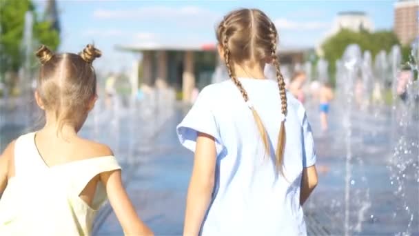 Urocze dziewczynki zabawy w ulicy fontanna w gorący słoneczny dzień — Wideo stockowe