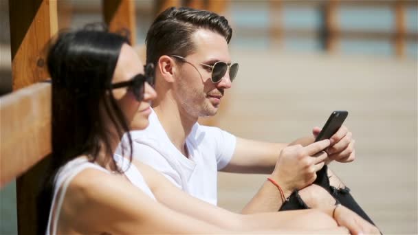 Imagen de una pareja alegre usando smartphones en el parque — Vídeos de Stock