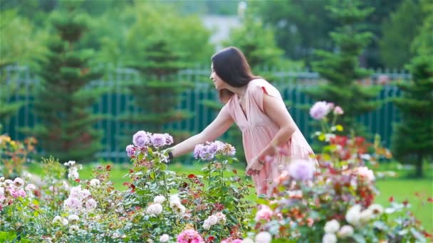 Jeune fille dans un jardin de fleurs parmi de belles roses. Odeur de roses — Video