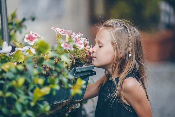 Roztomilá holčička, poblíž barevné květiny v zahradě — Stock fotografie