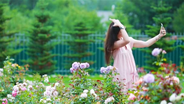 Jeune fille dans un jardin de fleurs parmi de belles roses. Odeur de roses — Video