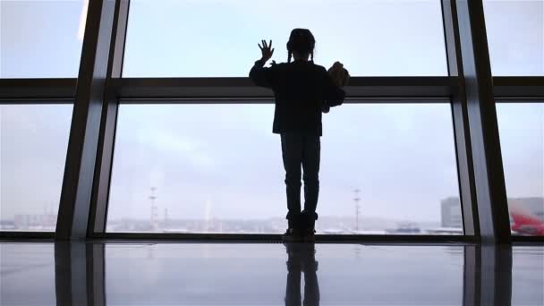 Havaalanında büyük pencerenin yanında küçük bir kız binişi bekliyor. — Stok video
