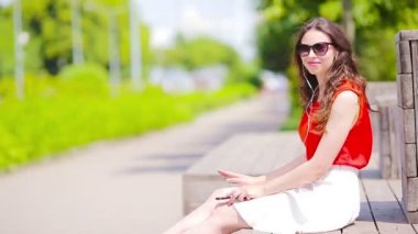 Güzel kız yaz tatillerini Smartphone'da tarafından müzik dinleme. Cep telefonu açık havada tatil zevk ile genç çekici turizm.