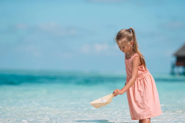 Schattig kind spelen met papier boten in een zee — Stockfoto