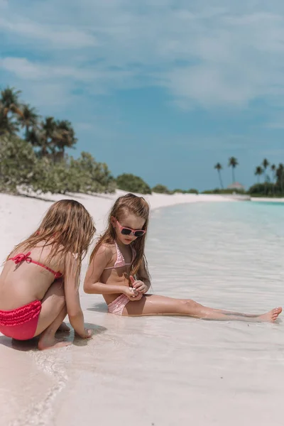 Dwie małe szczęśliwe dziewczyny mają dużo zabawy na tropikalnej plaży bawiąc się razem — Zdjęcie stockowe