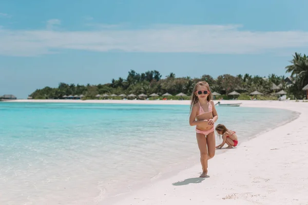 Zwei kleine glückliche Mädchen haben viel Spaß am tropischen Strand beim gemeinsamen Spielen — Stockfoto