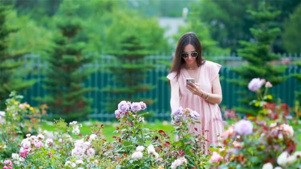 Mladá dívka v květinové zahradě mezi krásnými růžemi. Vůně růží — Stock video