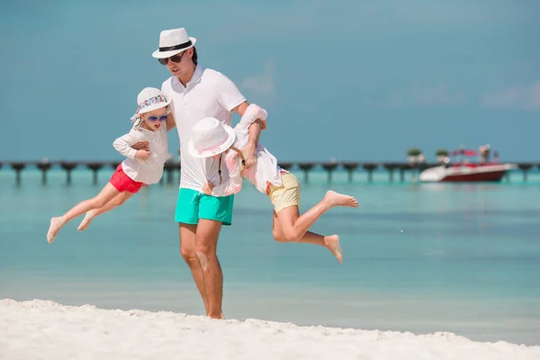 Счастливый отец и его очаровательные маленькие дочери на тропическом пляже веселятся — стоковое фото