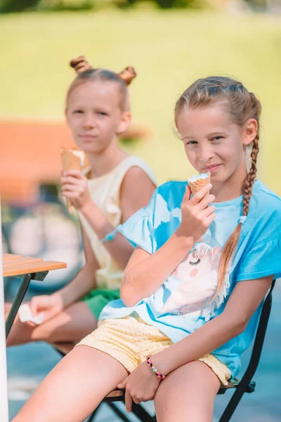 Malé dívky jíst zmrzlinu venku v létě, ve venkovní kavárně — Stock fotografie