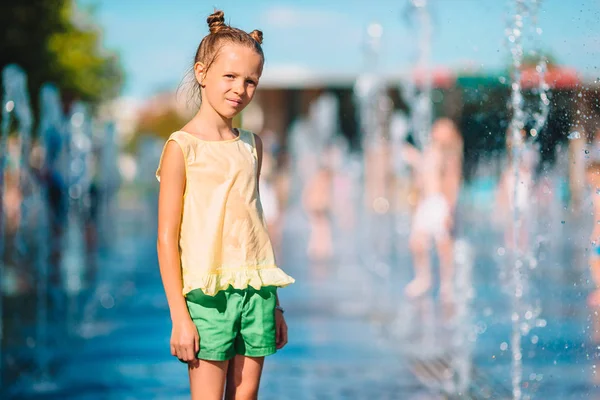 Pequena menina adorável se divertir na fonte da rua no dia ensolarado quente — Fotografia de Stock