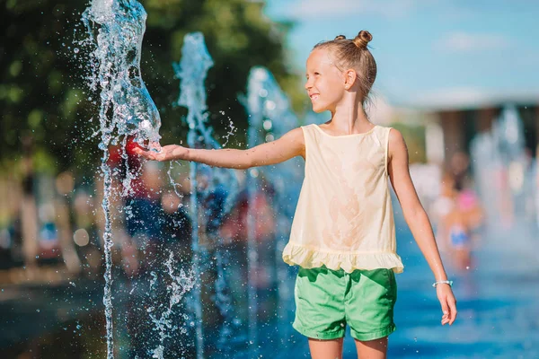 Schattig meisje plezier hebben in straat fontein op warme zonnige dag — Stockfoto