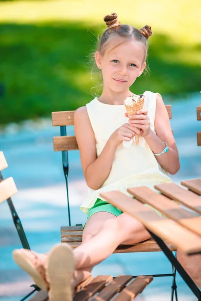 Küçük kız dondurma açık havada yaz aylarında açık kafe yeme. — Stok fotoğraf