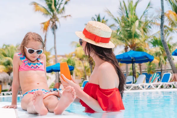 Jonge moeder zon crème toe te passen op de neus van het kind in zwembad — Stockfoto