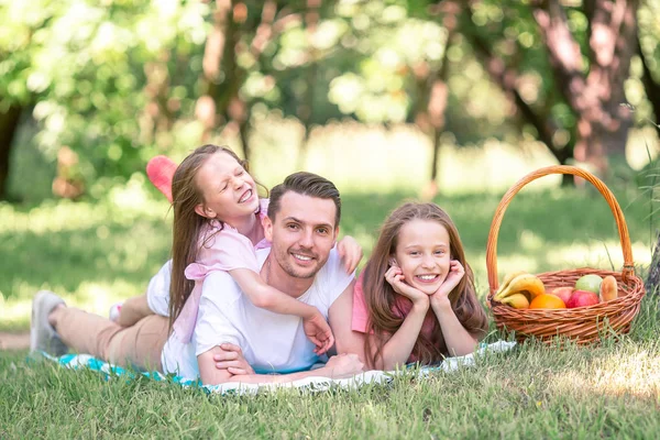 Счастливый отец и маленькие дочери отдыхают у озера — стоковое фото