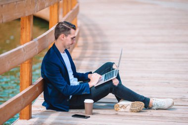 Parkta açık havada çalışan dizüstü bilgisayar ile genç adam