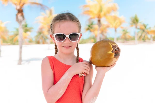 Little adorable girl with big coconut on sandy beach — Stock Photo, Image