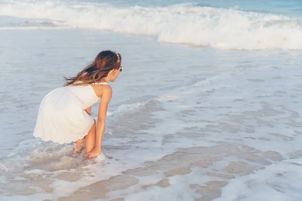 Liebenswertes kleines Mädchen am Strand, das viel Spaß im seichten Wasser hat — Stockfoto