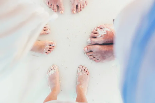 Gros plan des pieds de la famille sur la plage de sable blanc — Photo