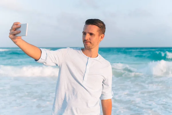 Ung man tar selfie på stranden bakgrunden havet — Stockfoto