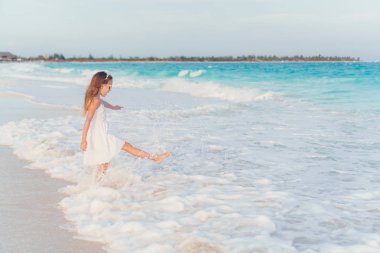 Kumsaldaki sevimli küçük kız sığ sularda çok eğleniyor.