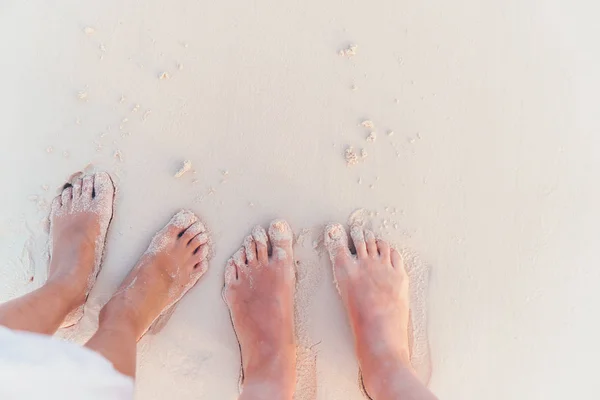 Gros plan des pieds de la famille sur la plage de sable blanc — Photo
