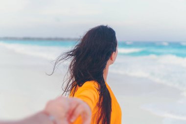 Erkek arkadaşı beyaz vahşi plajda gülerek ve gülümseyerek el ele takip