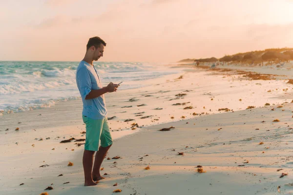 Ung man tar selfie på stranden bakgrunden havet — Stockfoto