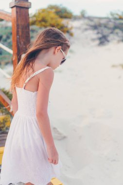 Kumsaldaki sevimli küçük kız sığ sularda çok eğleniyor.