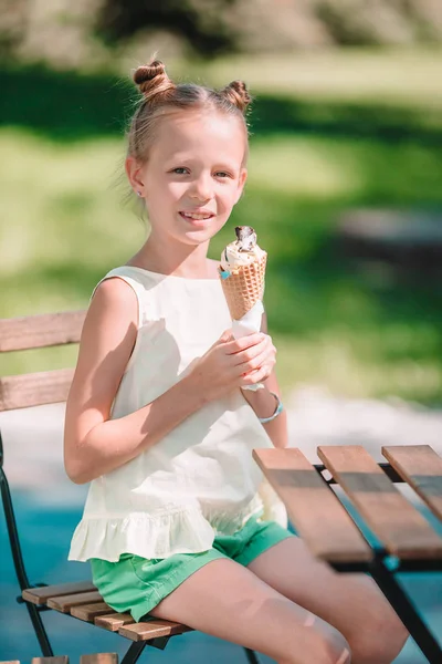 Little girl eating ice-cream outdoors at summer in outdoor cafe — Stock Photo, Image