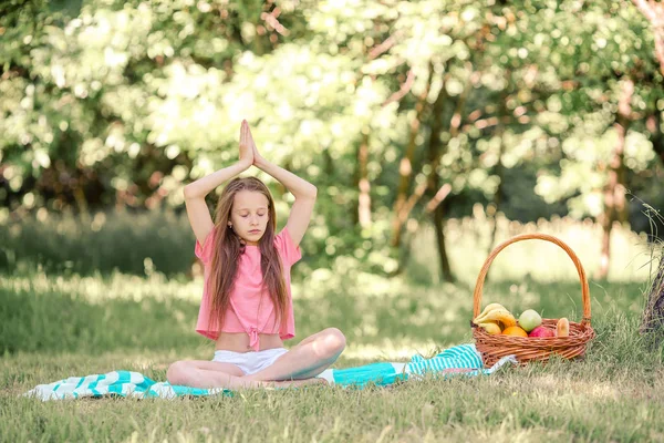 Petite fille en position de yoga dans le parc. — Photo