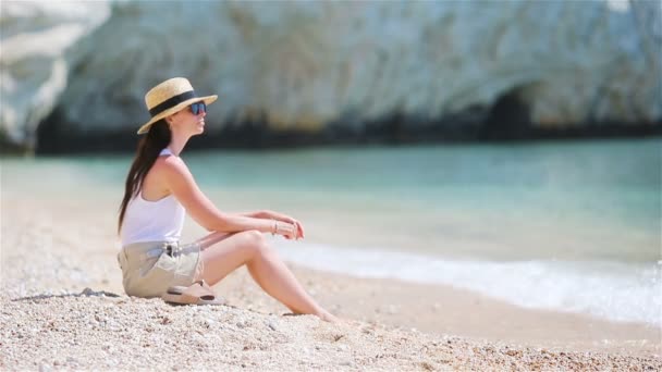Νεαρή όμορφη γυναίκα στην τροπική παραλία με λευκή άμμο. Καυκάσιος κορίτσι στο παρασκήνιο καπέλο στη θάλασσα — Αρχείο Βίντεο
