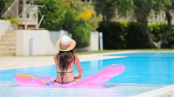 Jonge vrouw in bikini luchtmatras in het grote zwembad — Stockvideo