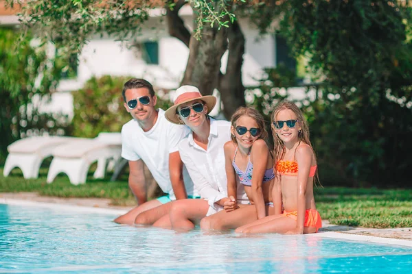 Família feliz de quatro pessoas na piscina — Fotografia de Stock