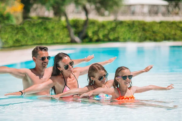 Familia feliz de cuatro en la piscina al aire libre — Foto de Stock